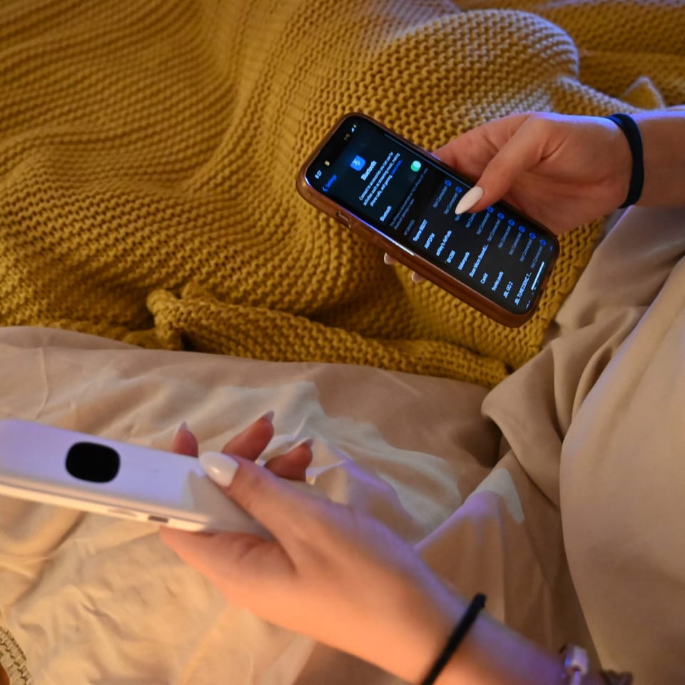 One hand holding a phone open on its Bluetooth list, the other holding the Lullabar.